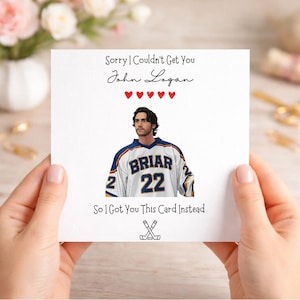 以下が含まれることがあります： 「Sorry I Couldn't Get You John Logan」と「So I Got You This Card Instead」のテキストが入った白いグリーティングカード。カードには、「BRIAR」の文字と「22」の数字が入ったホッケーのジャージを着た人のイラストが描かれています。