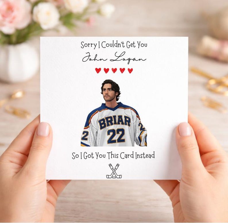 以下が含まれることがあります： 「Sorry I Couldn't Get You John Logan」と「So I Got You This Card Instead」のテキストが入った白いグリーティングカード。カードには、「BRIAR」の文字と「22」の数字が入ったホッケーのジャージを着た人のイラストが描かれています。