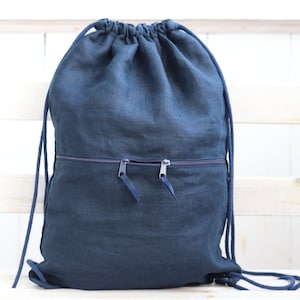 Può includere: Uno zaino blu scuro in lino con due tasche con cerniera sul davanti.