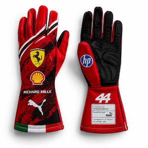 Peut inclure: Une paire de gants de course rouges et noirs arborant le logo Ferrari, l'emblème Shell, le texte Richard Mille et un logo Puma blanc. Les poignets affichent les couleurs du drapeau italien. La paume présente un logo HP, le numéro 44 et une étiquette FIA.