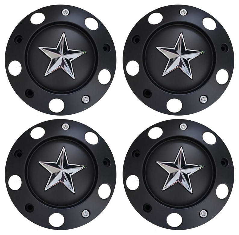 May include: Four black wheel center caps with a chrome star emblem in the center. Each cap has a series of small white circular holes around the edge and is secured with small screws.