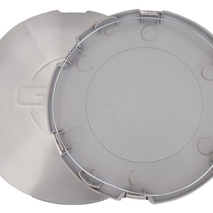 May include: Two-piece hubcap set. One piece is brushed metal with a stamped "G" logo. The other is a light gray plastic with a silver wire ring and several circular indentations. Automotive parts.