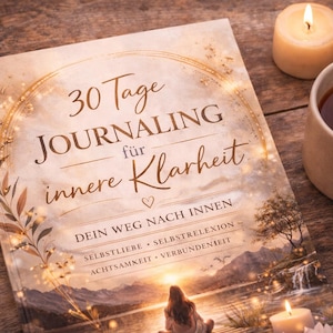 May include: A journal titled "30 Tage Journaling f&uuml;r innere Klarheit" sits on a wooden surface next to a lit candle and a mug of tea. The journal's cover features a scenic illustration and text in a script font. The scene is warm and inviting.