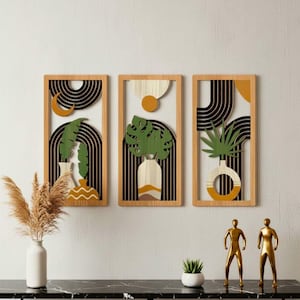 May include: Three rectangular wooden wall art panels featuring layered designs of vases with green tropical leaves, black arched lines, and yellow circular accents. The artwork displays a combination of natural wood tones, black, green, and mustard yellow colours.