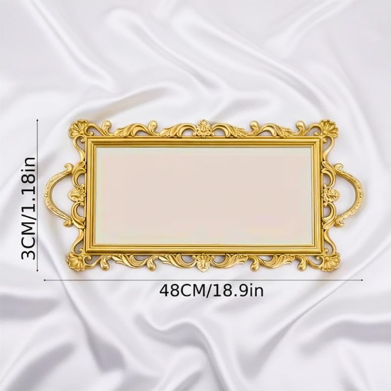 Pode incluir: Uma bandeja retangular dourada com uma moldura ornamentada de volutas e duas al&ccedil;as laterais. A bandeja apresenta uma superf&iacute;cie central lisa e plana. As dimens&otilde;es est&atilde;o claramente marcadas como 48 cm de comprimento e 3 cm de altura.