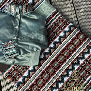Könnte beinhalten: Ein salbeigrünes Hemd mit Verzierungen an Kragen und Manschetten. Dazu ein Textil mit geometrischem Muster in Braun, Weiß und Türkis. Das Logo "STITCH AND STIRRUP" ist sichtbar.