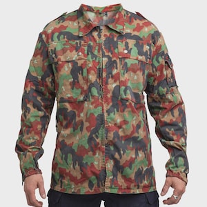 Può includere: Giacca mimetica con un vivace motivo rosso, verde, marrone e nero. La giacca presenta un collo, una chiusura con cerniera e più tasche. La giacca a maniche lunghe ha polsini con bottoni e spalline.