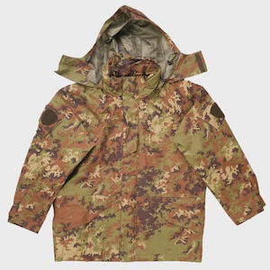 May include: A camouflage jacket with a hood. The jacket features a pattern of brown, green, and tan colors. It has a zipper closure and multiple pockets. Patches are visible on the sleeves. The jacket is designed for outdoor use.