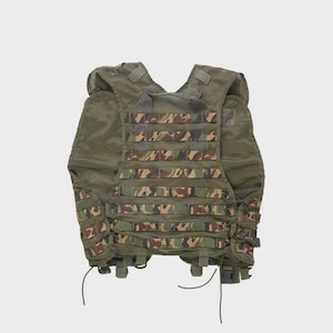 May include: A tactical vest in olive green mesh with camouflage accents. The vest features multiple straps and attachment points for gear. The camouflage pattern includes shades of brown, green, and tan. The vest is designed for military or outdoor use.