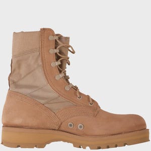 Könnte beinhalten: Beigefarbener Kampfstiefel mit Obermaterial aus Wildleder und Canvas. Der Stiefel verfügt über einen Schnürverschluss mit Metallösen, einen gepolsterten Kragen und eine strapazierfähige Gummisohle. Der Stiefel ist für den robusten Einsatz im Freien konzipiert.