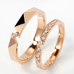 Könnte beinhalten: Zwei Ringe aus Roségold mit geometrischem Facettendesign. Ein Ring hat eine glatte, polierte Oberfläche mit einem kleinen Diamantakzent, während der andere Ring mit einer Reihe kleiner, funkelnder Diamanten in den Facetten besetzt ist.