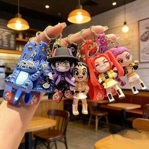 Puede incluir: Una colección de llaveros de personajes coloridos. Los llaveros presentan varias figuras de dibujos animados con diseños y colores distintos, incluyendo un gato azul, un personaje con abrigo y sombrero morados, y otros con trajes amarillos y rojos. Cada llavero tiene un anillo metálico.