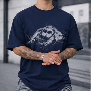Pu&ograve; includere: T-shirt blu navy con una dettagliata illustrazione di un ragno in tonalit&agrave; di grigio e bianco. La grafica &egrave; centrata sul petto. La t-shirt ha girocollo e maniche corte, uno stile casual.