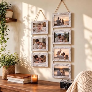 Peut inclure: Deux présentoirs photo muraux verticaux composés de cadres en bois blanc vieilli reliés par une corde de jute naturelle. Le présentoir de gauche contient trois cadres rectangulaires et celui de droite en contient quatre, affichant des photos de famille.