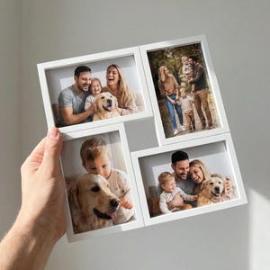 May include: A white multi-photo frame holding four family photos. The photos feature families with children and dogs. The frame is held by a person's hand against a plain white background. The photos are in rectangular frames.