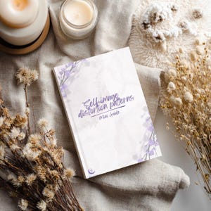 May include: A rectangular booklet with a white cover featuring a light purple floral branch design in the corners. The text on the cover reads Self-image distortion patterns Mini Guide in purple script and print, with a small crescent moon logo.