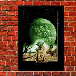 May include: A framed Star Wars art print featuring Yoda in a meditative pose, set against a green planet and starry background. The artwork has a vintage, sepia-toned aesthetic, with a black frame and a brick wall backdrop.