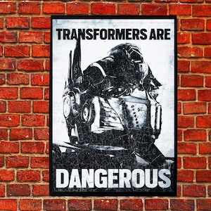 Pode incluir: Pôster em preto e branco com uma imagem desgastada da cabeça de um Transformer. O texto "TRANSFORMERS ARE DANGEROUS" é exibido em letras brancas em negrito. O pôster é emoldurado em preto e montado em uma parede de tijolos vermelhos.