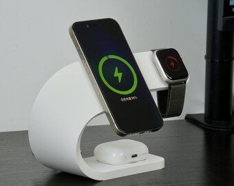 May include: White charging station with a curved design, holding a black smartphone, a smartwatch, and a white wireless charging case. The phone screen shows a green charging symbol. The smartwatch shows a red charging symbol.