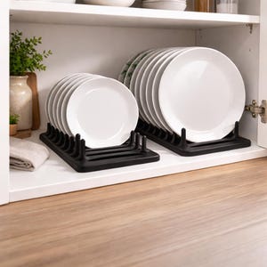 Op de afbeelding: Twee zwarte bordenrekken met stapels witte borden in een witte kast. De borden zijn rond en hebben een eenvoudig ontwerp. De rekken zijn gemaakt van donker materiaal en hebben verticale verdelers om de borden rechtop te houden.