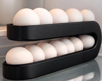 May include: A black, two-tier egg holder filled with white eggs, inside a fridge. The holder is made of a matte black material and is designed to hold a dozen eggs. The eggs are visible and neatly arranged.