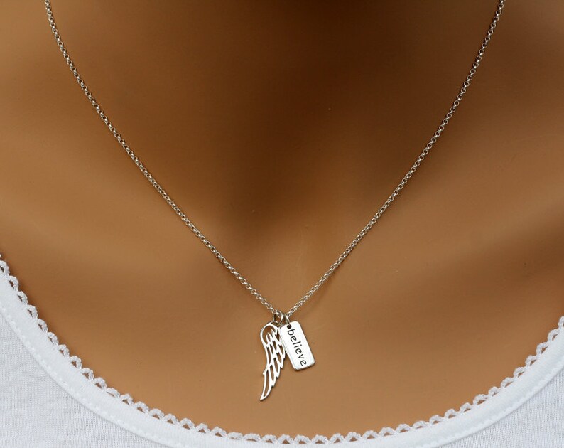 May include: A silver chain necklace with a small silver charm that says "believe" and a silver angel wing pendant.