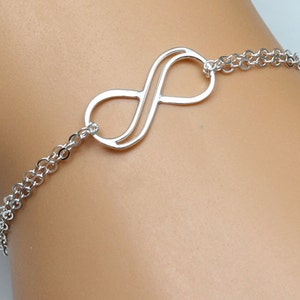 May include: A silver infinity symbol charm bracelet with a delicate chain. The bracelet is made of sterling silver and is a popular choice for gifts.