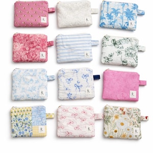 May include: Twelve rectangular fabric zip pouches arranged in a grid. Each pouch features a unique pattern, including floral, striped, and botanical prints in various colours like pink, blue, white, and yellow. Each has a small white brand tag.