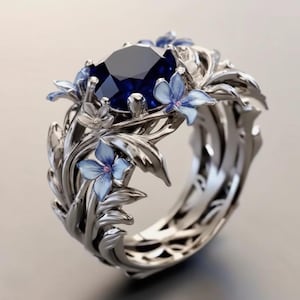 Puede incluir: Anillo plateado con una gran piedra preciosa azul oscuro en el centro. El anillo está adornado con delicadas flores y hojas de color azul claro, creando un diseño floral. La banda tiene un diseño calado, lo que se suma a los intrincados detalles del anillo.