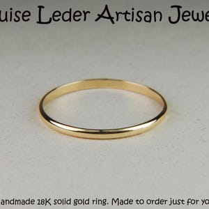 May include: A thin, polished 18K solid gold ring with a smooth, rounded band. The text Louise Leder Artisan Jewelry is at the top, and the text Handmade 18K solid gold ring. Made to order just for you. is at the bottom of the image.