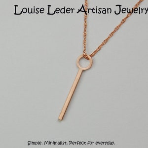 Puede incluir: Collar con colgante de color oro rosa con un dise&ntilde;o minimalista en forma de llave. El colgante cuelga de una delicada cadena. El collar es sencillo y perfecto para el uso diario. El texto "Louise Leder Artisan Jewelry" est&aacute; en la parte superior.