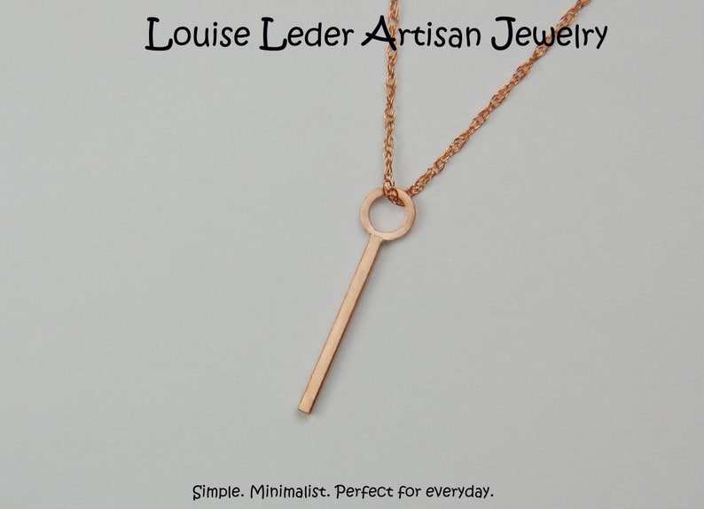Puede incluir: Collar con colgante de color oro rosa con un dise&ntilde;o minimalista en forma de llave. El colgante cuelga de una delicada cadena. El collar es sencillo y perfecto para el uso diario. El texto "Louise Leder Artisan Jewelry" est&aacute; en la parte superior.