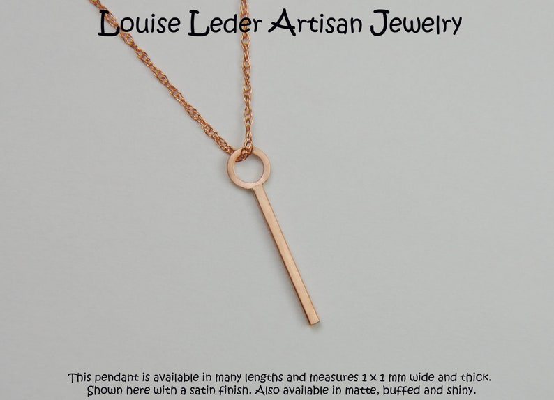 Puede incluir: Collar con colgante de oro rosa de dise&ntilde;o minimalista. El colgante es una barra recta con una parte superior circular, suspendida de una delicada cadena. El colgante mide aproximadamente 1 mm de ancho y grosor. El texto "Louise Leder Artisan Jewelry" est&aacute; arriba.