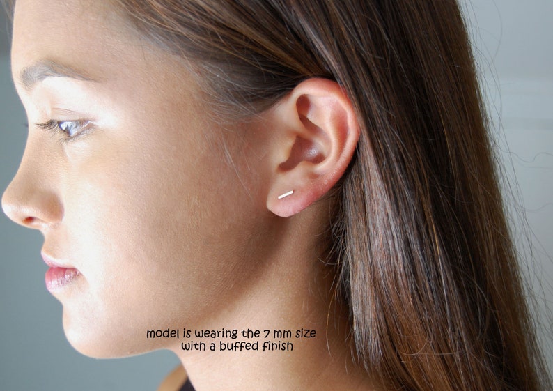 Puede incluir: Primer plano de la oreja de una persona con un peque&ntilde;o pendiente de barra de plata. La modelo lleva la talla de 7 mm con un acabado pulido.