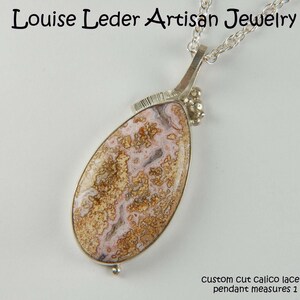 Puede incluir: Un collar de plata con un colgante de &aacute;gata de encaje calic&oacute; cortado a medida. El colgante mide 4,7 cm de largo. Louise Leder Artisan Jewelry.