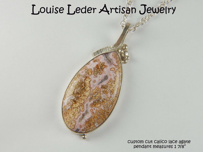 Puede incluir: Un collar de plata con un colgante de &aacute;gata de encaje calic&oacute; cortado a medida. El colgante mide 4,7 cm de largo. Louise Leder Artisan Jewelry.