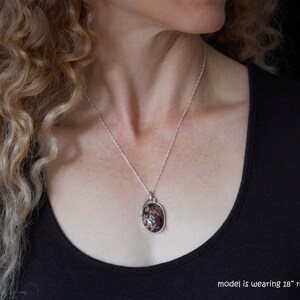 May include: A silver necklace with a red and white oval pendant. The model is wearing an 18" rope chain.