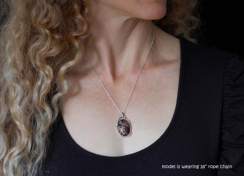 May include: A silver necklace with a red and white oval pendant. The model is wearing an 18" rope chain.