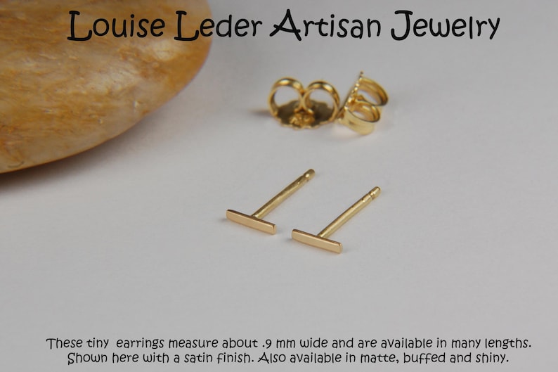 May include: Gold-colored bar stud earrings with a satin finish, displayed with earring backs. The earrings are approximately .9 mm wide. The text "Louise Leder Artisan Jewelry" is at the top, and additional text is at the bottom.