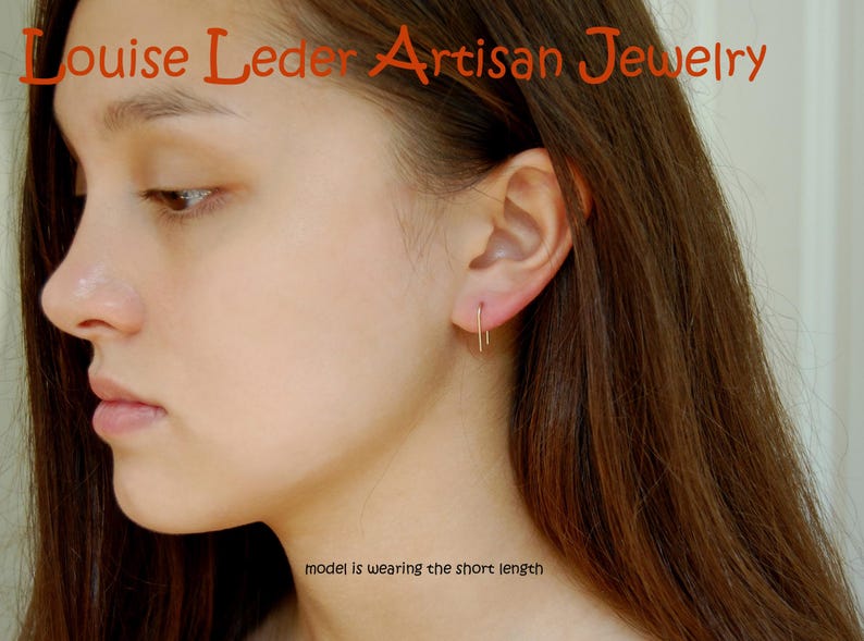 May include: A thin, gold-toned U-shaped earring worn in the earlobe. The text 'Louise Leder Artisan Jewelry' appears at the top, and the text 'model is wearing the short length' is positioned near the bottom of the image.