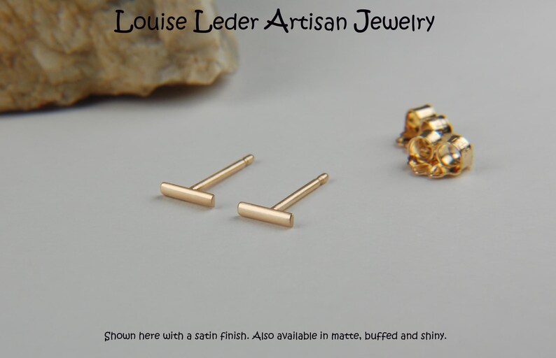 Puede incluir: Un par de pendientes de barra de oro. Los pendientes se muestran con un acabado satinado. El texto "Louise Leder Artisan Jewelry" est&aacute; en la parte superior de la imagen. El texto "Shown here with a satin finish. Also available in matte, buffed and shiny." est&aacute; en la parte inferior de la imagen.