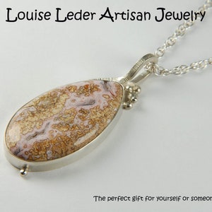 Puede incluir: Un collar de cadena de plata con un colgante en forma de l&aacute;grima con una piedra de &aacute;gata marr&oacute;n y rosa.