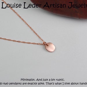Puede incluir: Un collar minimalista de oro rosa con un peque&ntilde;o colgante redondo. La delicada cadena y el colgante se muestran sobre un fondo neutro. El texto "Louise Leder Artisan Jewelry" est&aacute; en la parte superior.