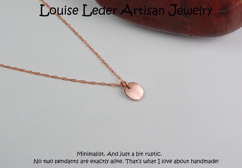 Puede incluir: Un collar minimalista de oro rosa con un peque&ntilde;o colgante redondo. La delicada cadena y el colgante se muestran sobre un fondo neutro. El texto "Louise Leder Artisan Jewelry" est&aacute; en la parte superior.