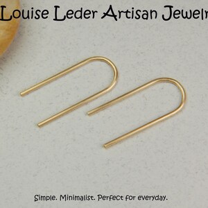 Puede incluir: Un par de pendientes minimalistas de color dorado con un dise&ntilde;o simple y curvado. Simple. Minimalista. Perfecto para todos los d&iacute;as.