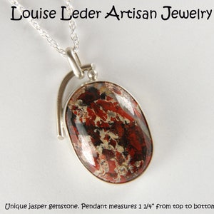 May include: A silver pendant with a unique jasper gemstone. The gemstone is red, black, and white with a swirling pattern. The pendant measures 1 1/4 inches from top to bottom.