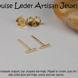 May include: Gold bar-shaped stud earrings with posts and ear backs. The earrings are handmade and made of 18K solid gold. The image also includes the text "Louise Leder Artisan Jewelry".