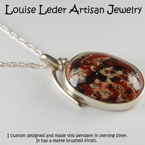 May include: A silver pendant with a red, black, and white stone. The pendant has a matte brushed finish. "I custom designed and made this pendant in sterling silver. It has a matte brushed finish."