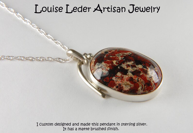 May include: A silver pendant with a red, black, and white stone. The pendant has a matte brushed finish. "I custom designed and made this pendant in sterling silver. It has a matte brushed finish."