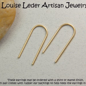 Puede incluir: Un par de pendientes de aro abierto minimalistas de color dorado. Los pendientes est&aacute;n hechos de metal fino y liso y tienen un dise&ntilde;o simple y discreto.